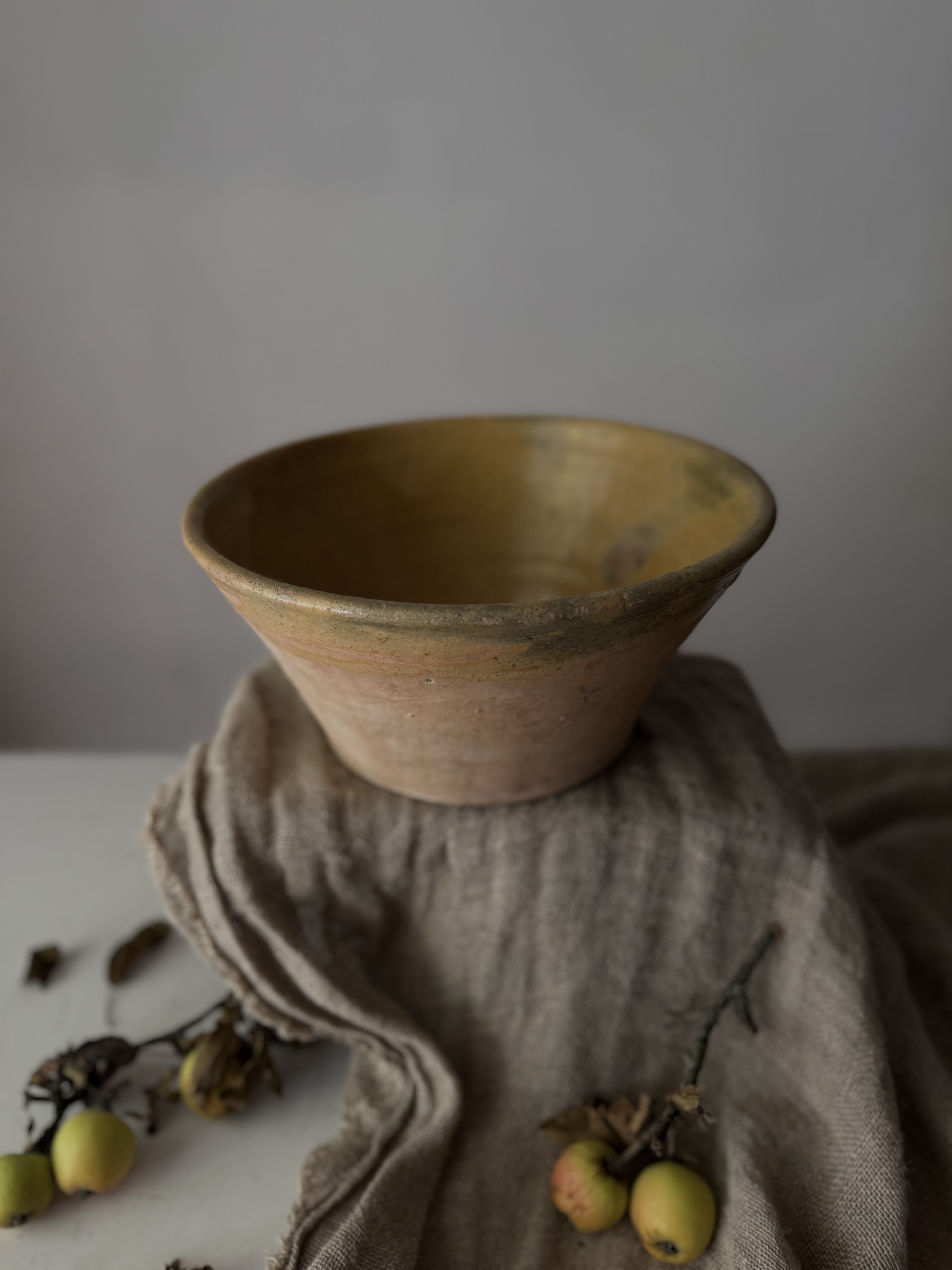 Profile view of the rustic French tian bowl resting on natural linen