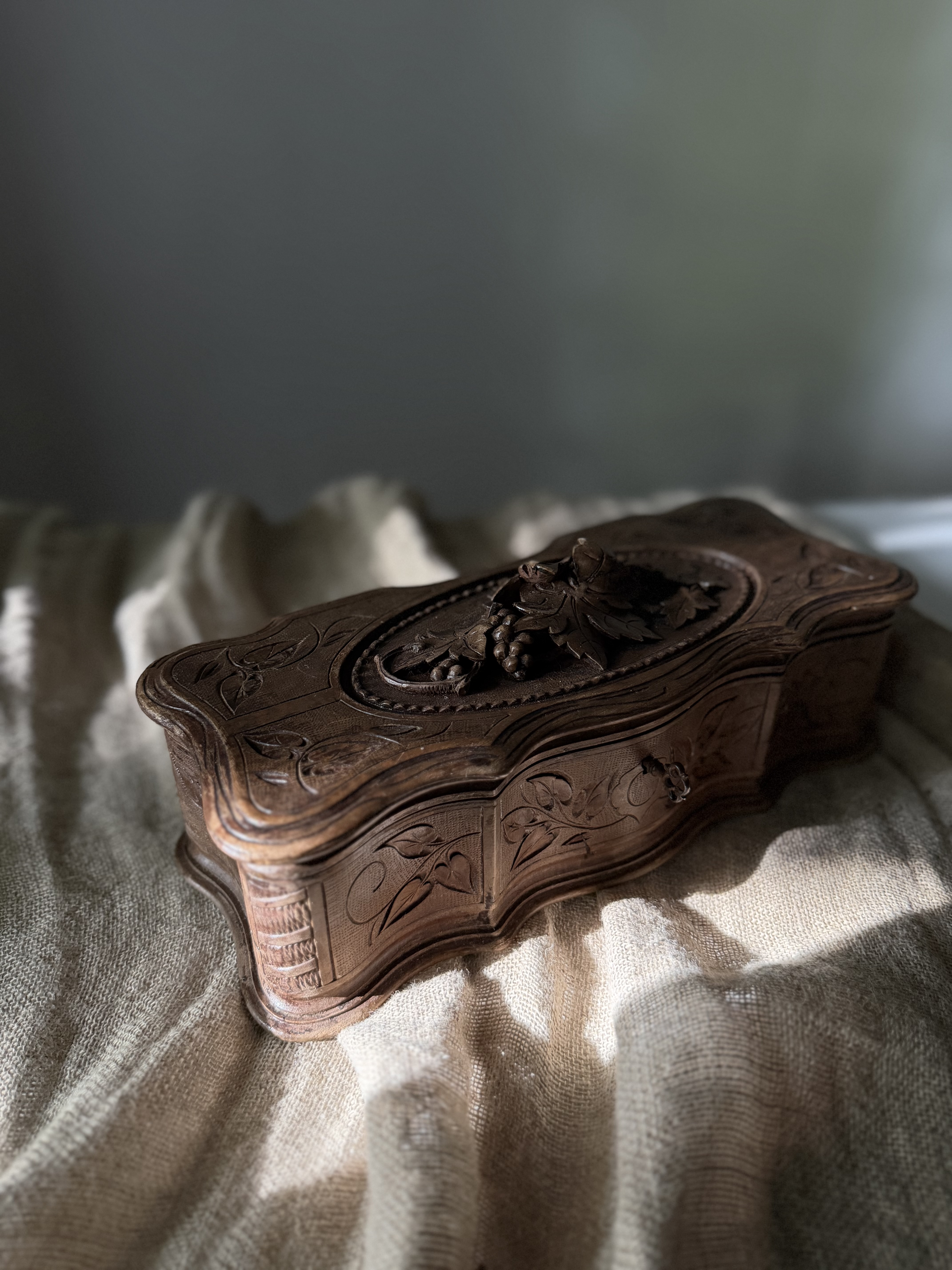 Macro detail of the high-relief carved grape clusters and foliage on the lid