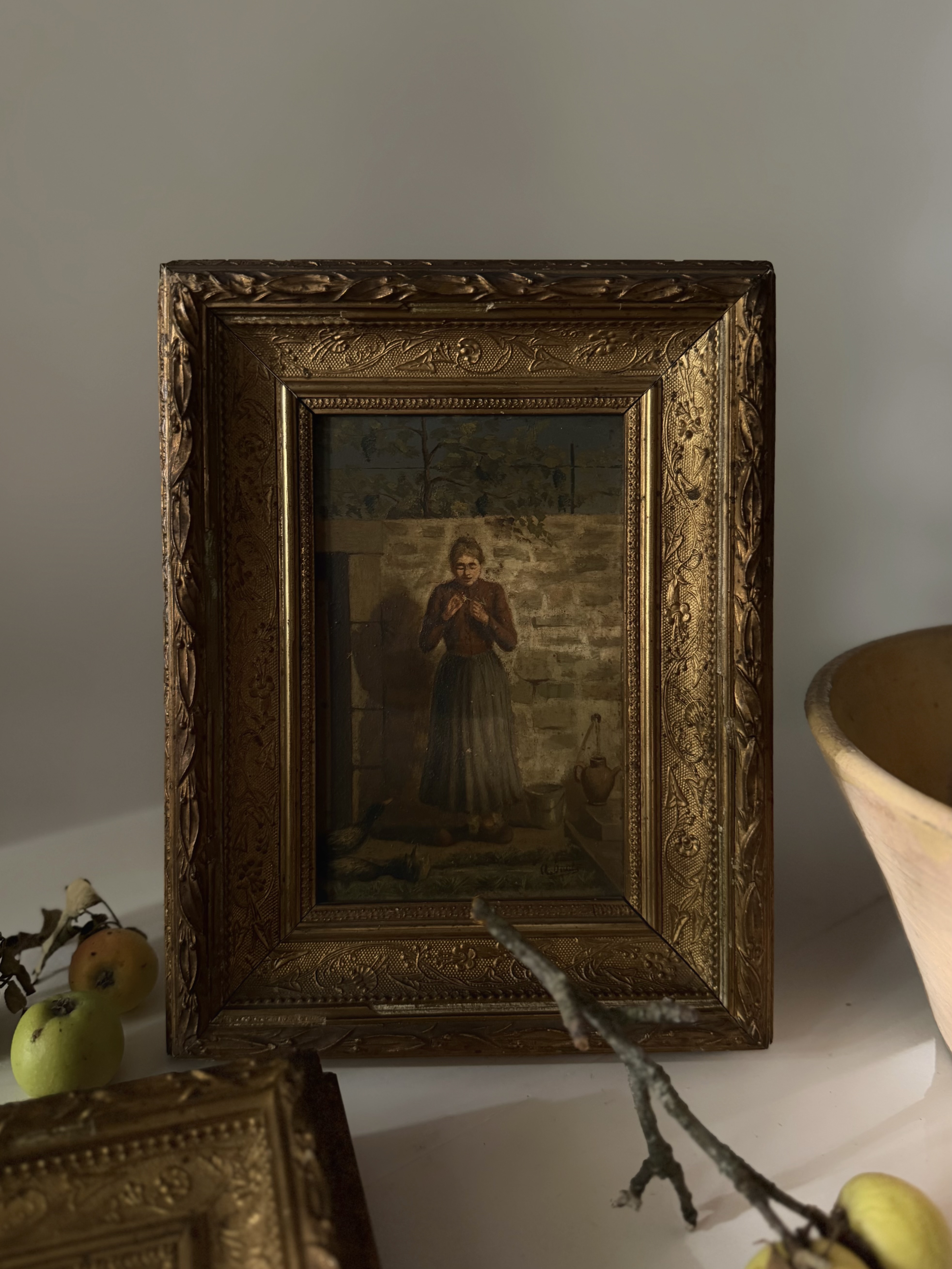 Antique oil painting of a rural French woman standing near a stone wall